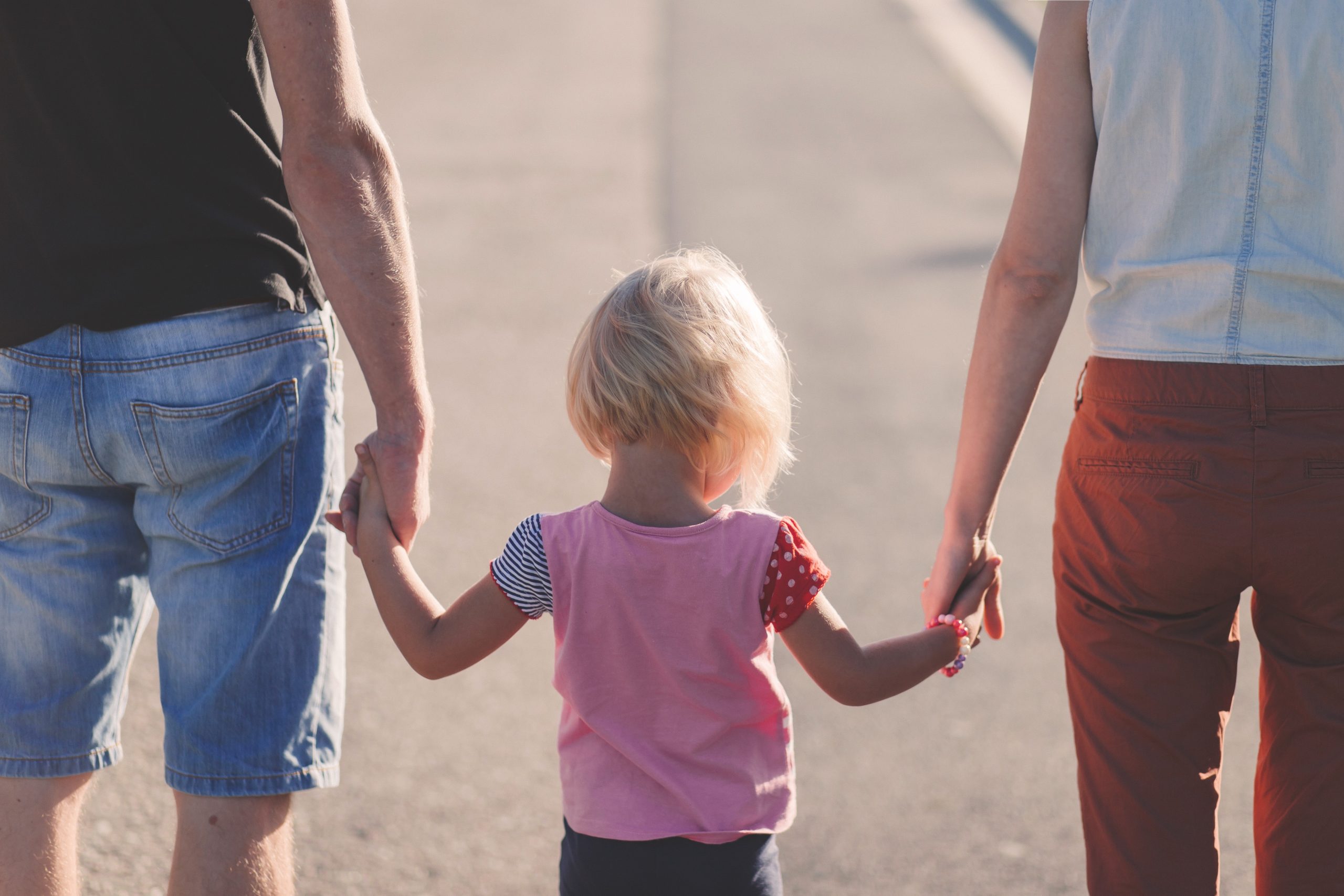 homepage a young child holding the hands of both parents